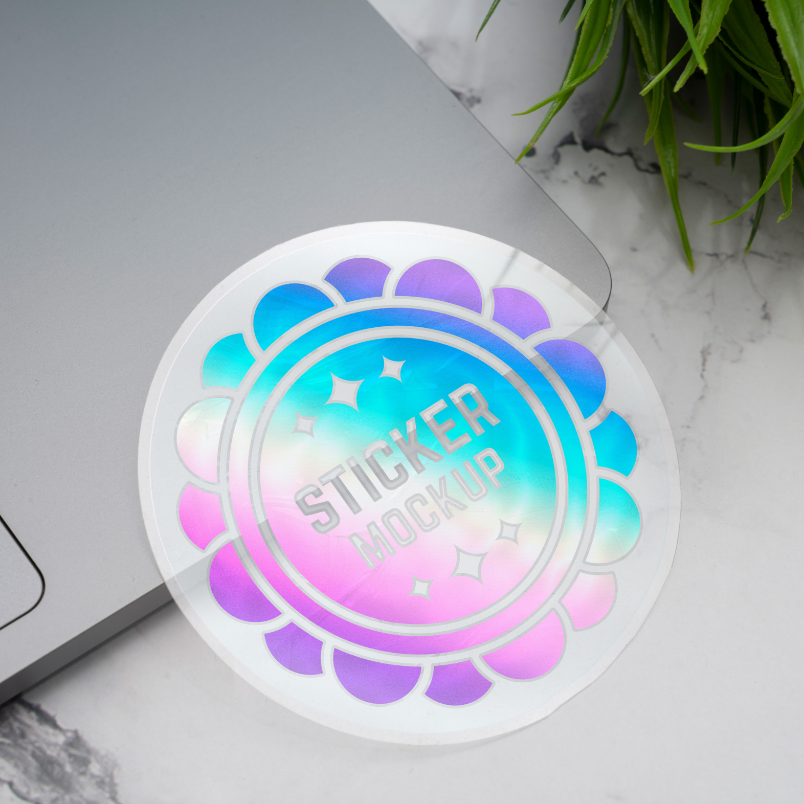 Holographic sticker mockup on a marble surface with a laptop and plant in the background