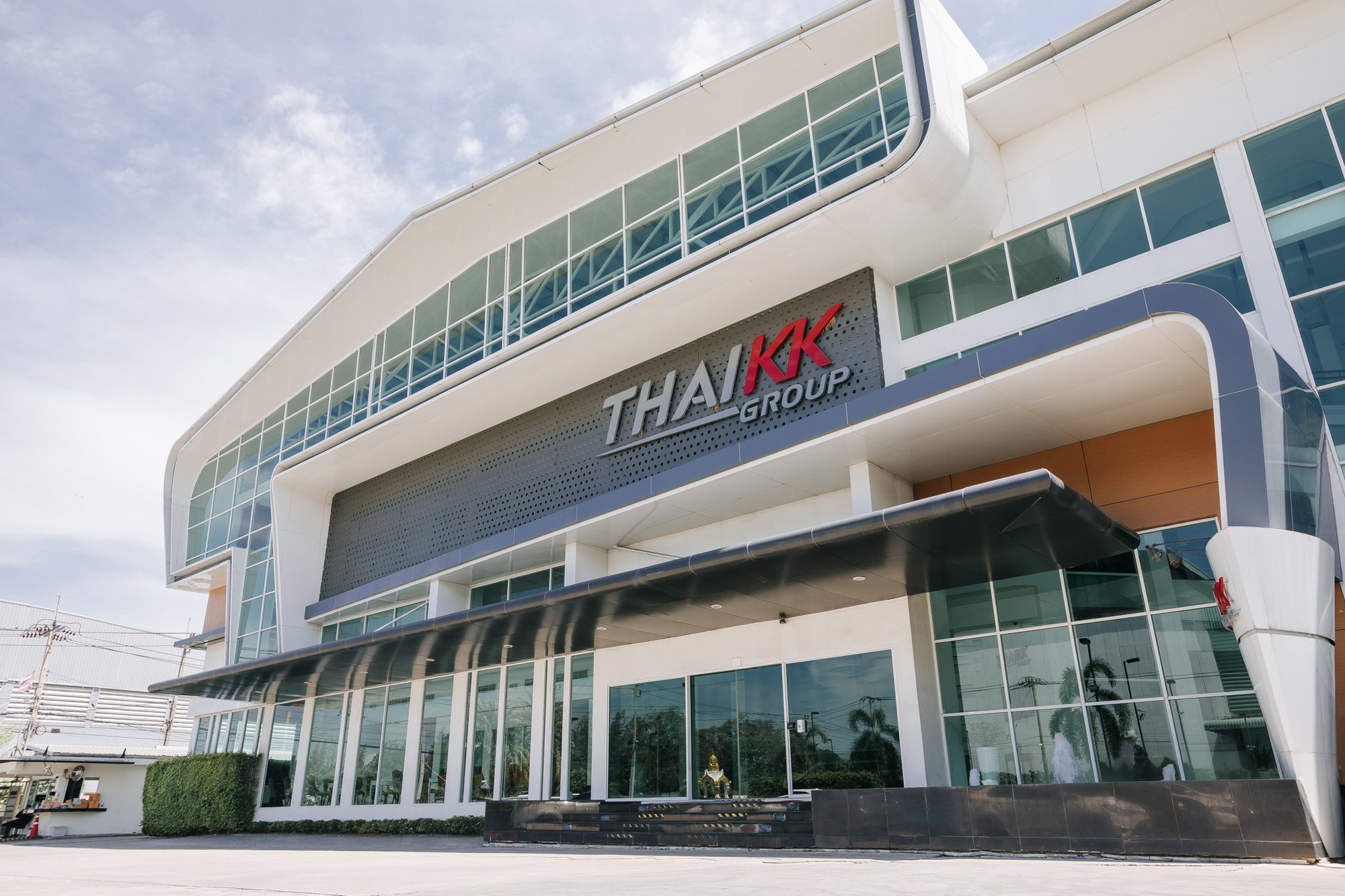Modern office building with 'THAI KK GROUP' signage on a clear day